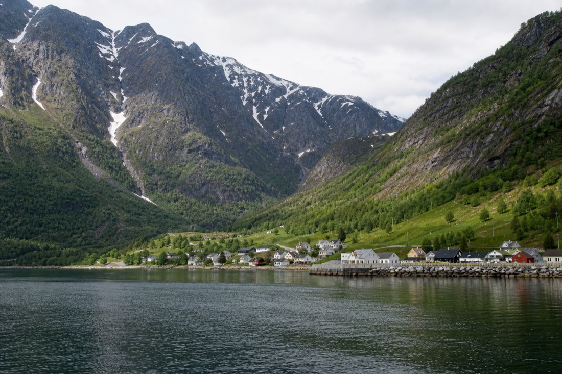 Fjord village in late spring with melting snow on the peaks and green grass on the lower slopes