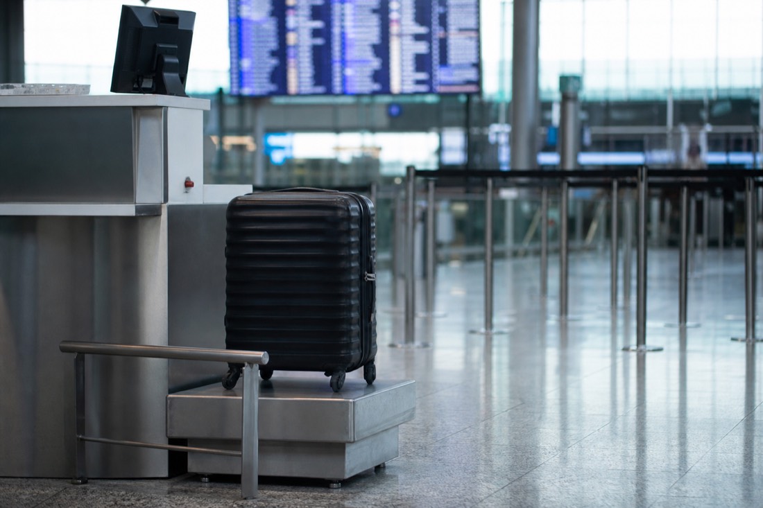 Airport check-in area with a suitcase on a baggage scale and a departure board behind