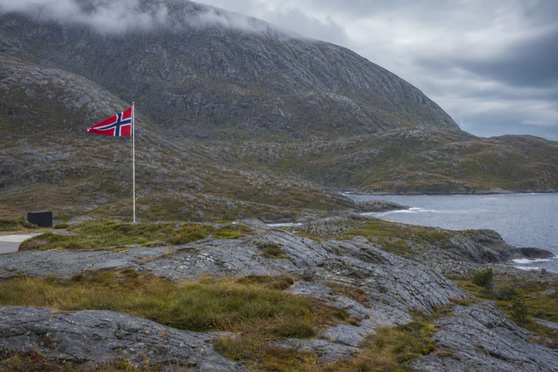 Norwegian border control desk with the national flag and an arrivals sign above a quiet airport corridor