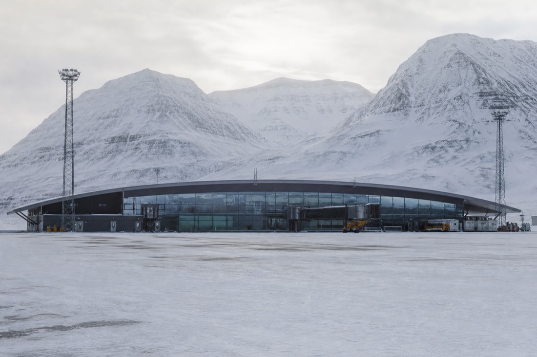 Small Arctic airport terminal exterior in snow with mountains behind