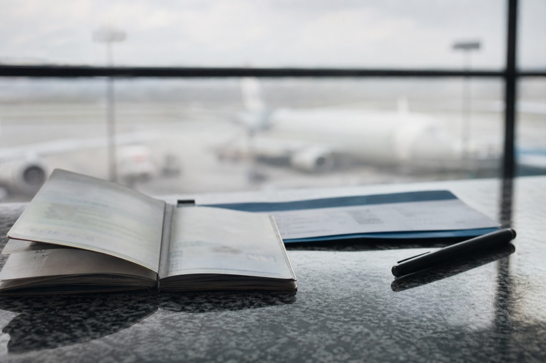 Passport and boarding pass on a counter beside a pen