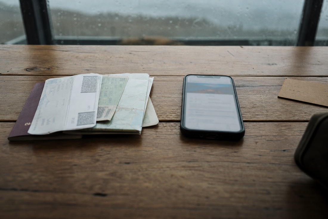 Travel documents and a phone on a wooden table