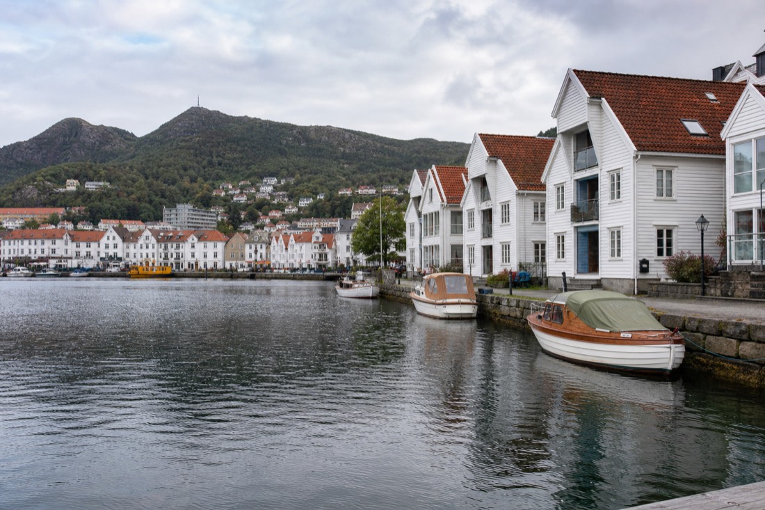 Harbour front of a Norwegian coastal city with white wooden houses and moored boats