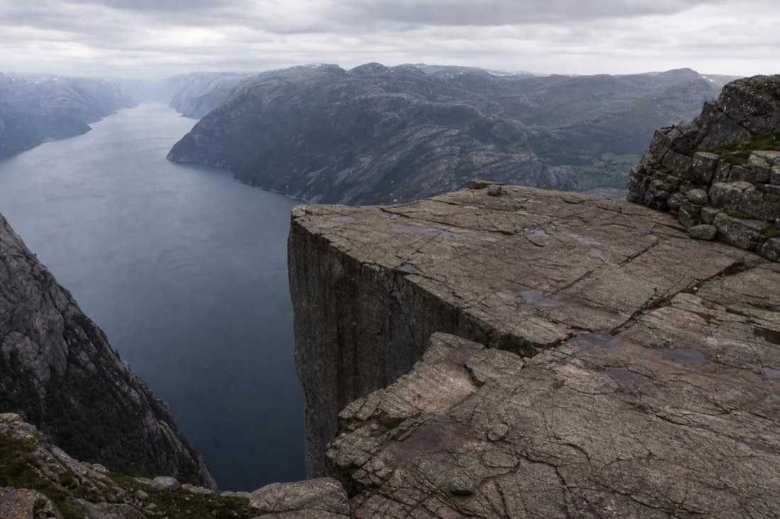 Wide flat rock plateau above a narrow fjord with steep cliffs falling to the water