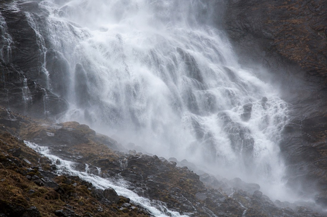 Powerful waterfall in full flow down a dark rock face with spray in the air