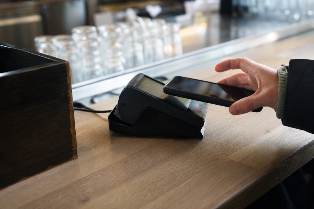 Contactless card payment on a terminal held by a hand at a Norwegian counter