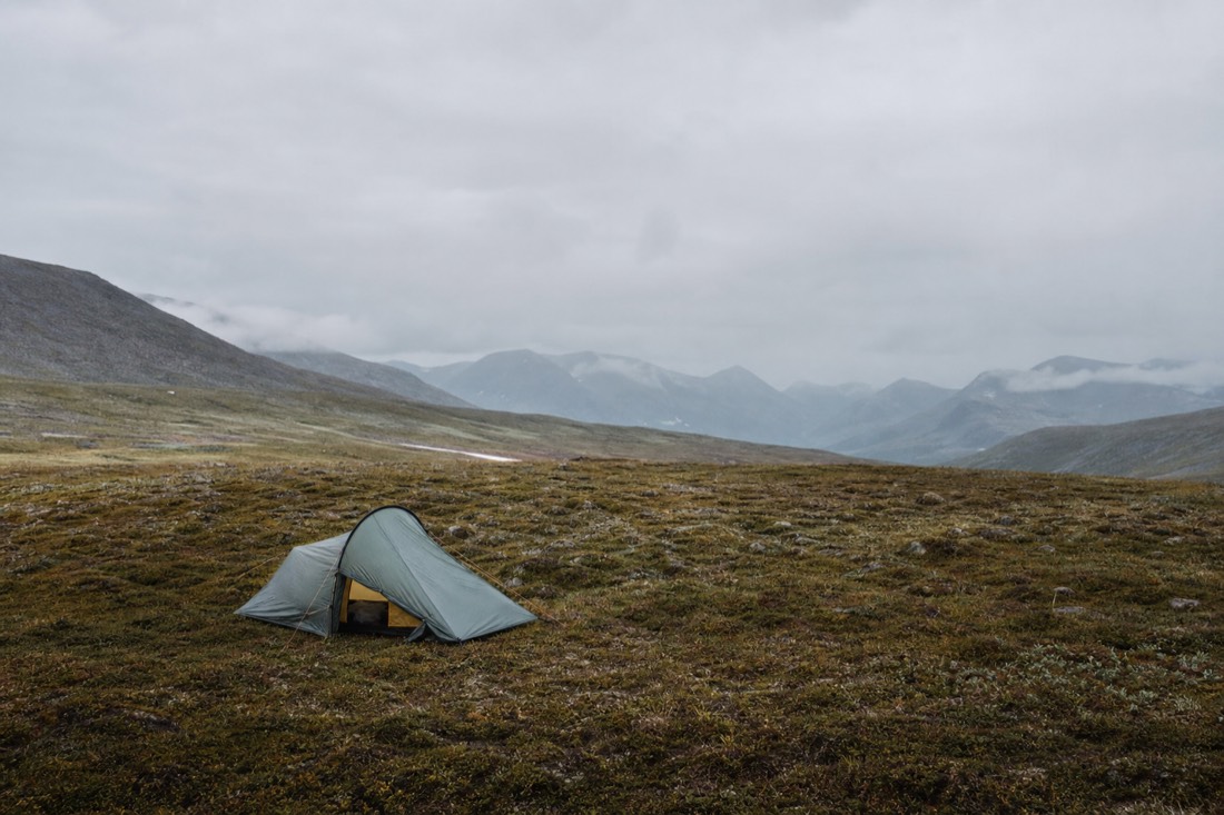 Small tent pitched on open ground well away from any buildings under grey sky