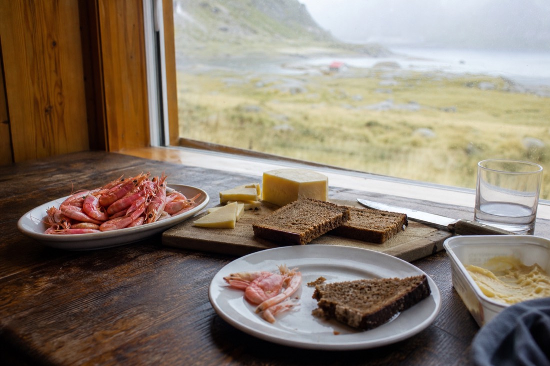 Simple meal of bread, cheese and shrimp laid out on a cabin table by a window