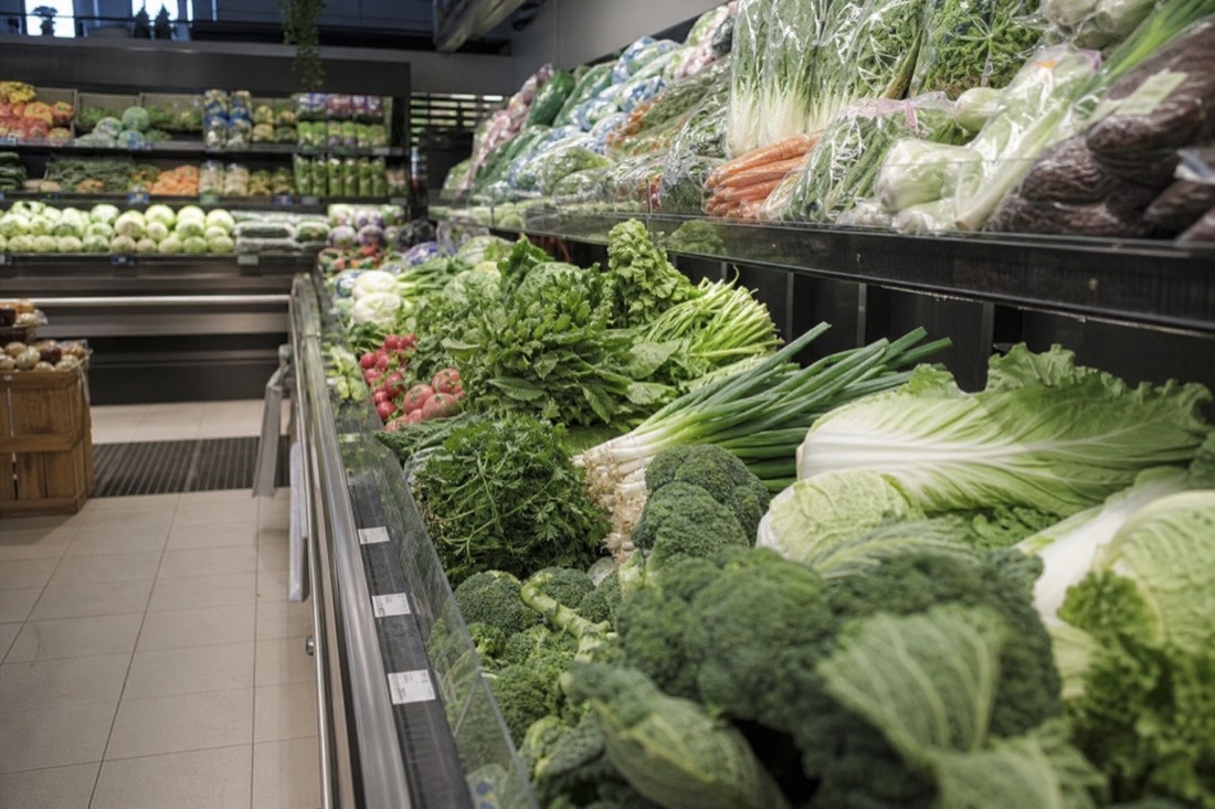 Supermarket produce aisle with fresh vegetables under bright light