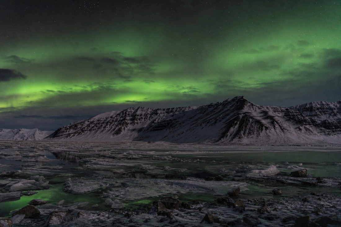 Dark Arctic landscape at night with faint green light above a ridge and no artificial lighting