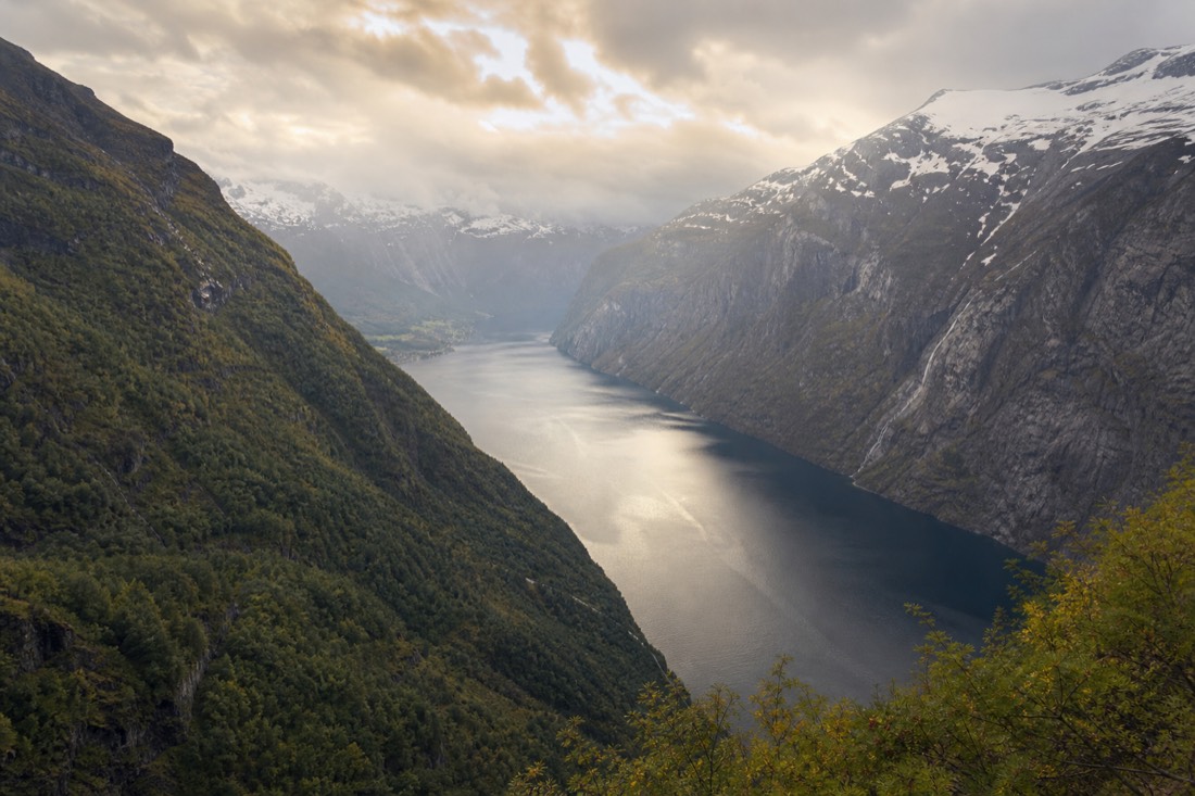 Two framed viewpoints of the same fjord, one green and summery and one under snow