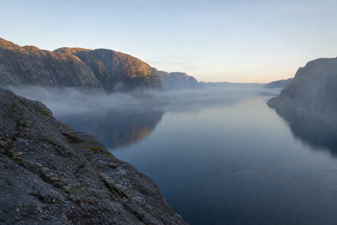 Early morning at an empty fjord viewpoint with mist on the water and no people