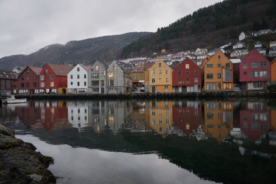 Wooden quayside houses in Bergen reflected in still harbour water on a grey morning