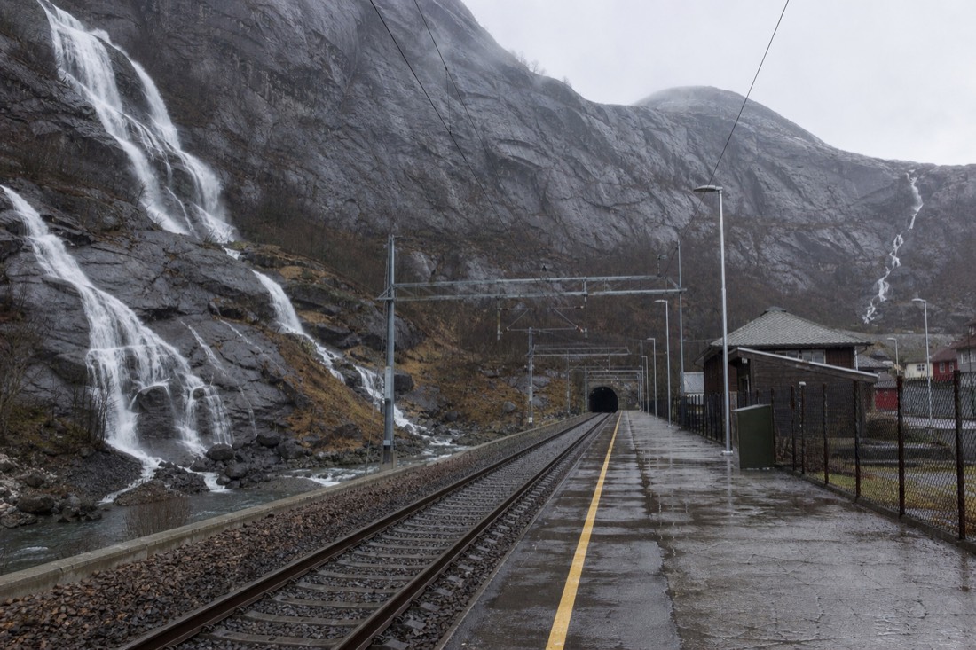 Empty railway platform in a Norwegian mountain village with bare rock slopes rising behind
