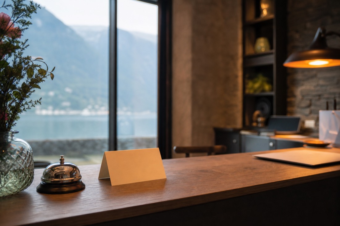 Reception desk of a small Norwegian hotel with a folded card stand and fjord light coming through the window