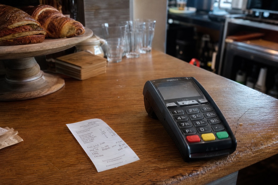 Card payment terminal on a wooden counter in a Norwegian cafe with a receipt beside it