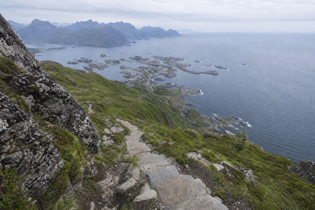 Stone staircase climbing steeply up a green Lofoten mountainside with the sea far below
