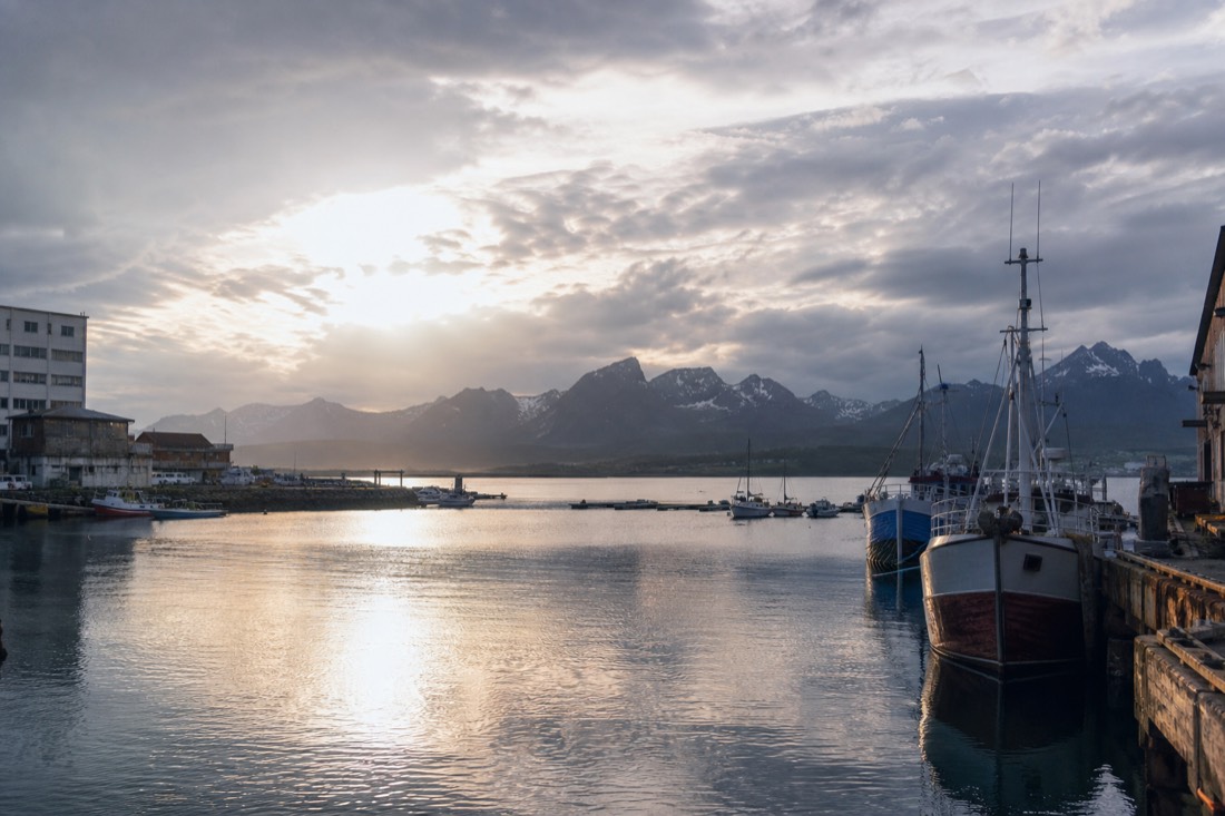 Bright daylight at midnight over a northern Norwegian harbour with still water and moored boats