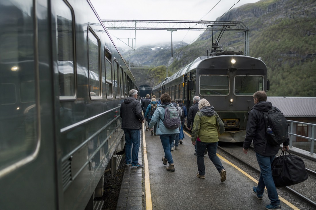 Passengers hurrying along a small mountain station platform between a mainline train and a waiting local service
