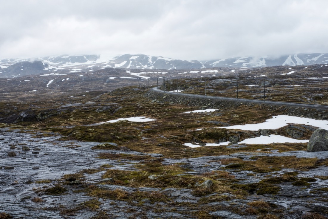 Empty mountain plateau on the Bergen railway line with snow patches, low scrub and a distant track curving away