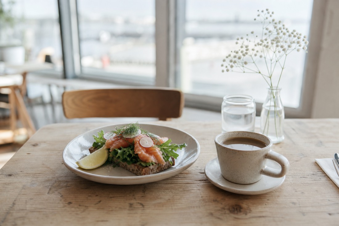 Simple weekday lunch plate and coffee on a wooden table in a bright Nordic cafe