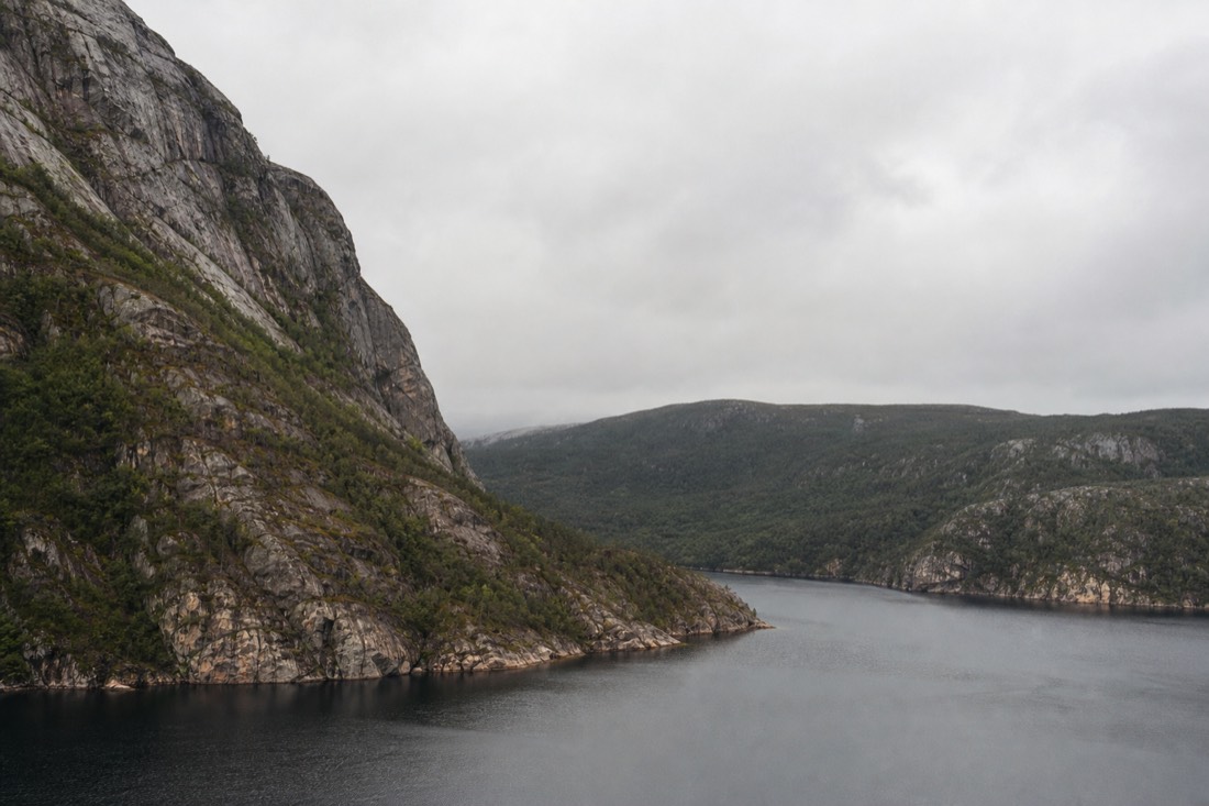 Comparison-style landscape of a deep fjord on one side and flat pine forest with a lake on the other