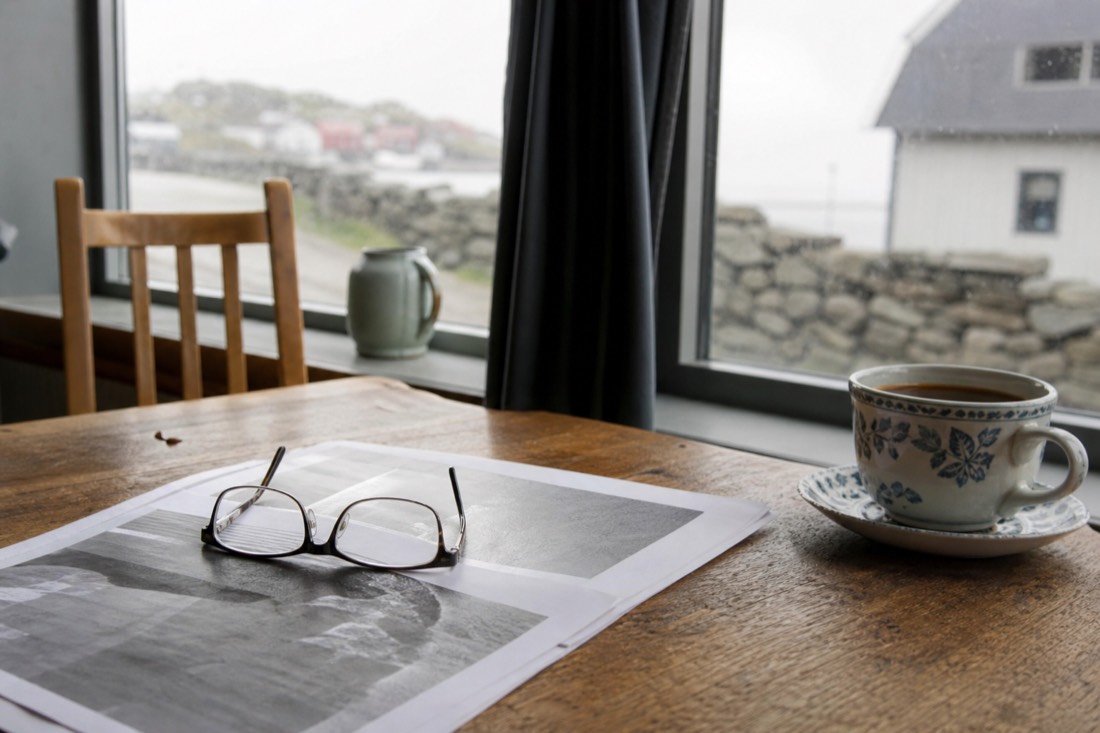 Reading glasses resting on a printed insurance document beside a cup of tea on a table
