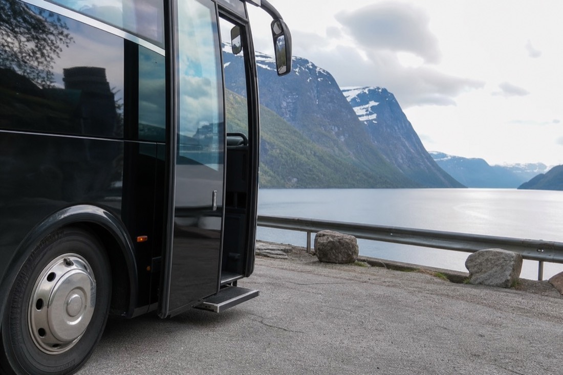 Coach parked at a fjord-side viewpoint with its door open and a low step down to level ground