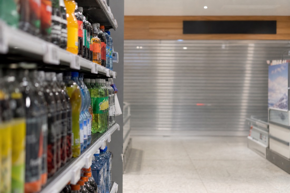 Shelf of a Norwegian supermarket with bottled drinks and a closed shutter beyond