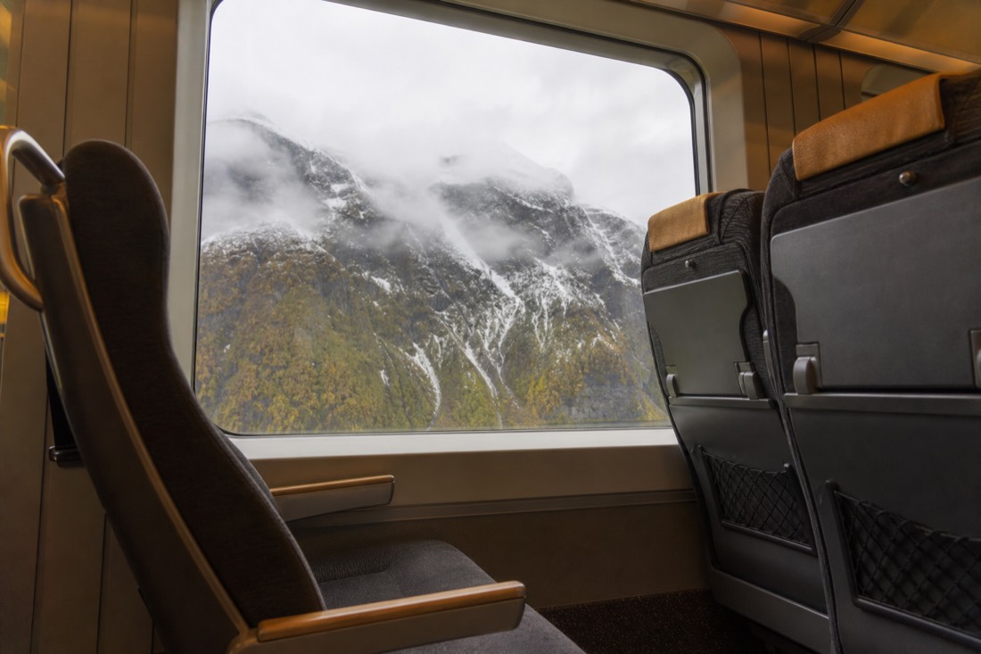Norwegian railway carriage interior with a window seat and mountain scenery passing outside