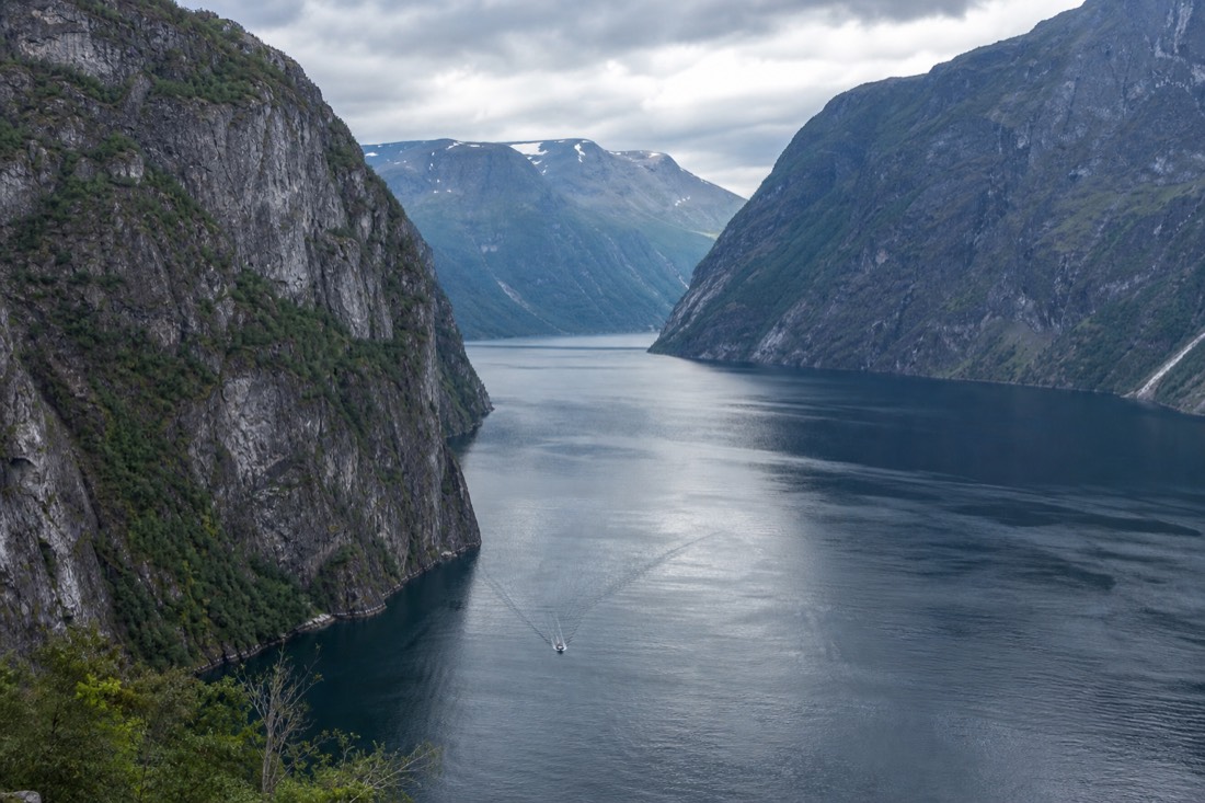 Narrow fjord arm with sheer walls on both sides and a small boat far below for scale