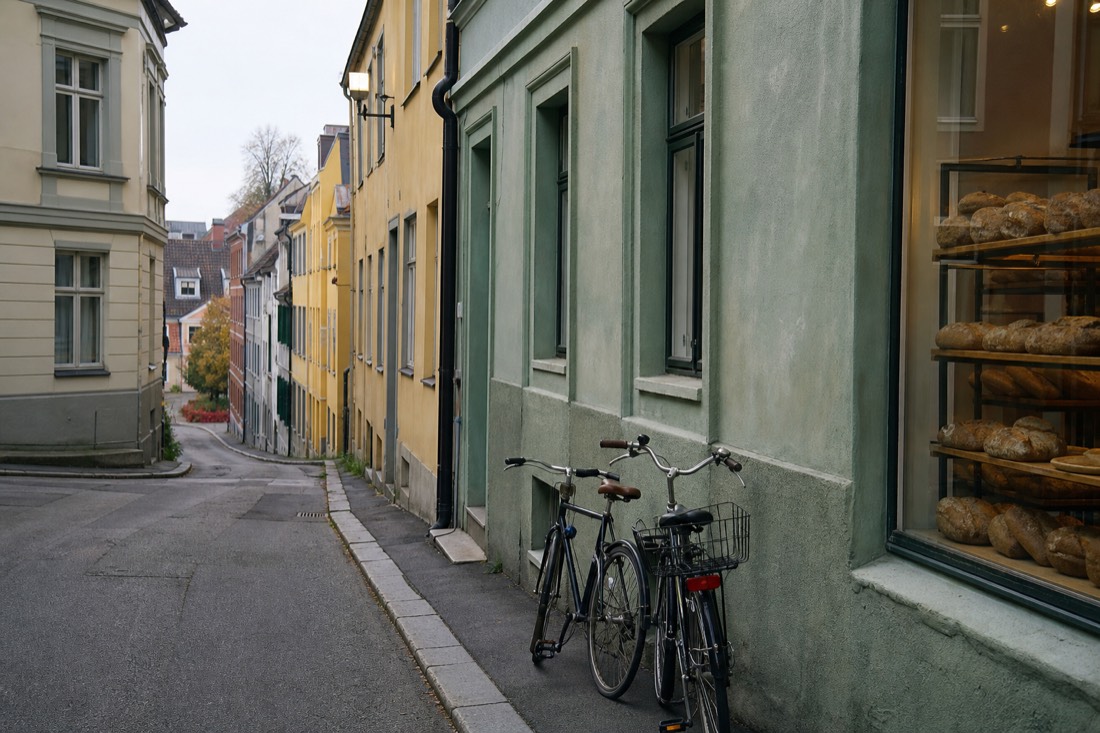 Narrow Oslo side street with a small bakery window and bicycles leaning against the wall