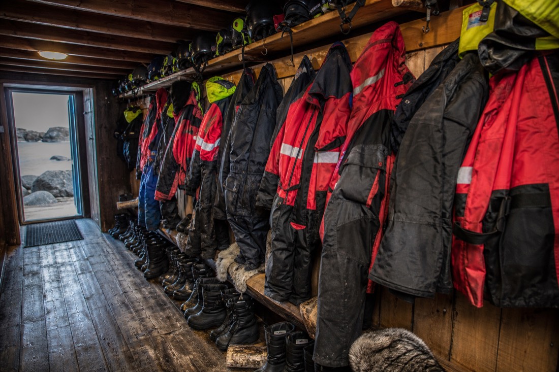 Row of insulated thermal suits and winter boots hanging in a heated Arctic tour base cabin